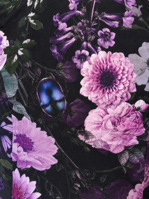 Detail van de Enchanted Garden-print met paarse en roze bloemen, groene bladeren en een blauwe kever